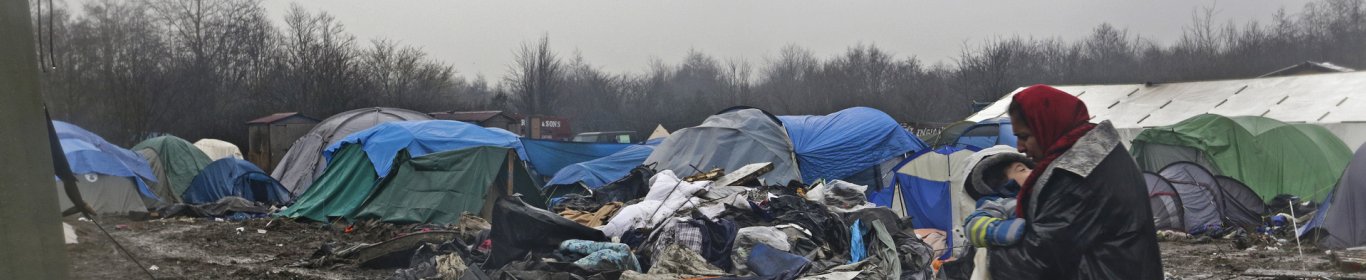 Une femme porte un enfant dans le camp de Grande Synthe