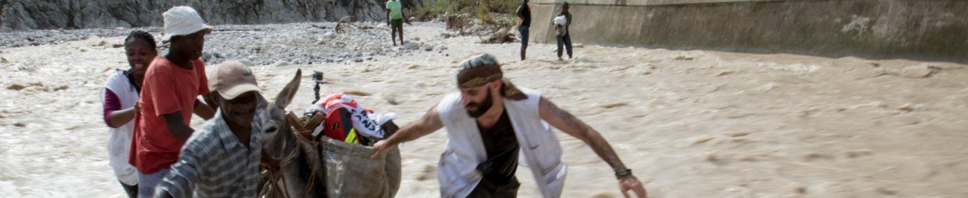 Un membre de MSF aide des habitants à traverser une zone inondée en Haiti