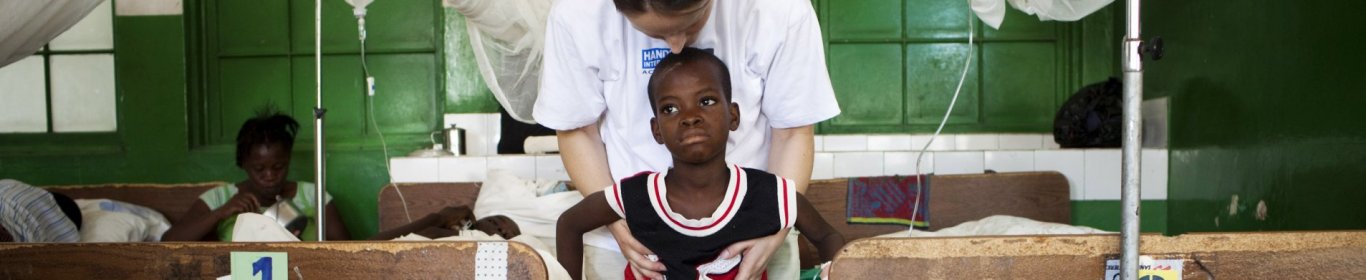 Un travailleur MSF aide un enfant qui a perdu une jambe à se tenir debout