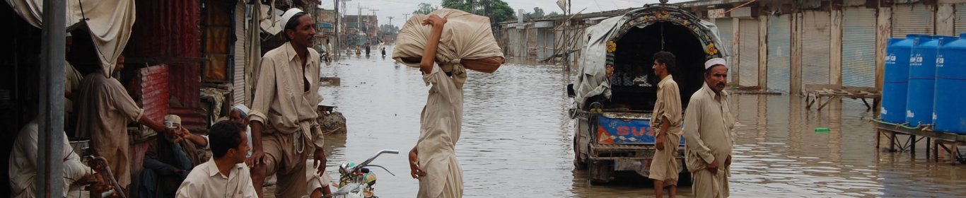 Des hommes discutent dans une rue inondée de Nowshera au Pakistan