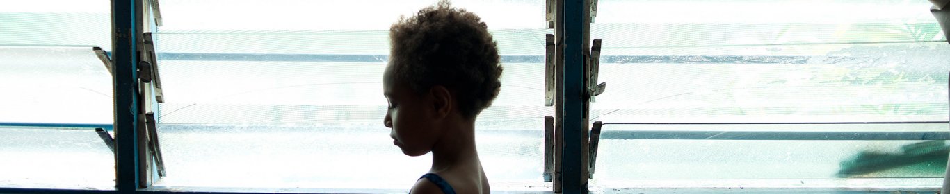 Une petite fille de 6 ans se tient debout devant une fenêtre, dans un centre MSF en Papouasie Nouvelle Guinée