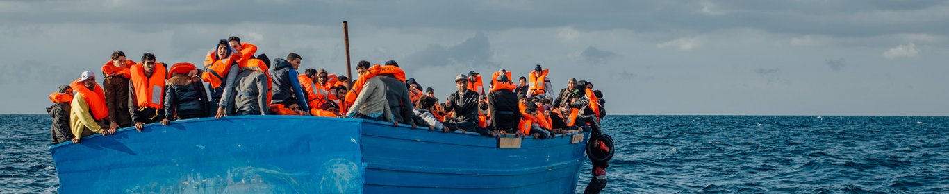 un homme s'accroche à un bateau de migrants, à proximité des côtés libyennes