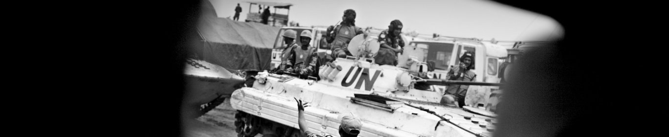 un soldat se tient debout devant un char des Nations unies