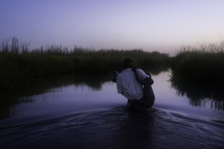 un membre de MSF aide un garçon à rejoindre Kok Island