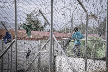 Jeune homme derrière les grilles d'un camp de détention en Grèce