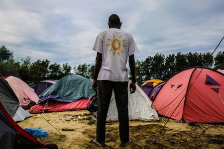 Un homme est debout devant les tentes d'un camp de réfugiés