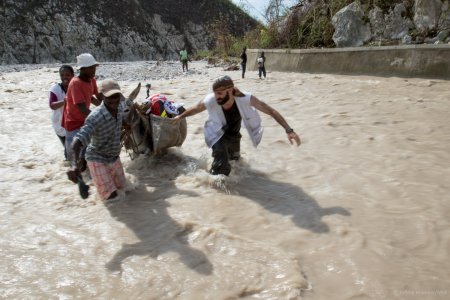 Un membre de MSF aide des habitants à traverser une zone inondée en Haiti