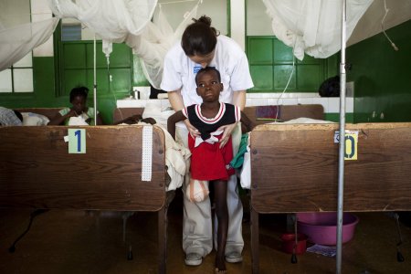 Un travailleur MSF aide un enfant qui a perdu une jambe à se tenir debout