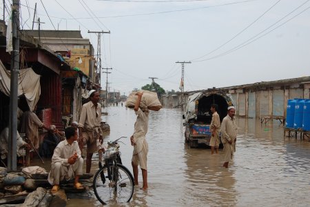 Des hommes discutent dans une rue inondée de Nowshera au Pakistan