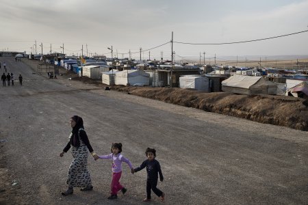 Une femme et deux enfants traversent une route dans le camp de réfugiés de Domiz, au Kurdistan Irakien