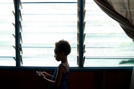 Une petite fille de 6 ans se tient debout devant une fenêtre, dans un centre MSF en Papouasie Nouvelle Guinée
