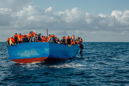 un homme s'accroche à un bateau de migrants, à proximité des côtés libyennes