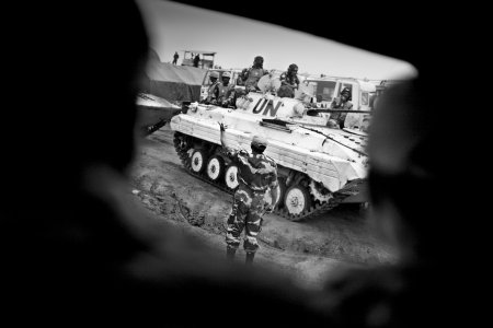 un soldat se tient debout devant un char des Nations unies