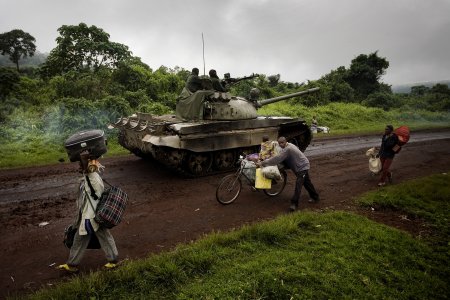 Un tank s'avance sur une route tandis que des personnes s'enfuient en sens inverse.  Kibumba, est du Congo. 
